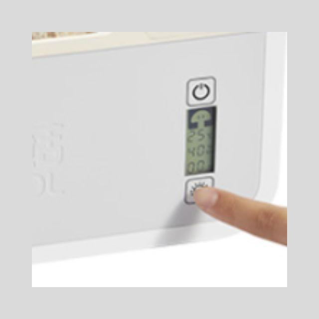 Digital thermometer being held by a finger against a white background