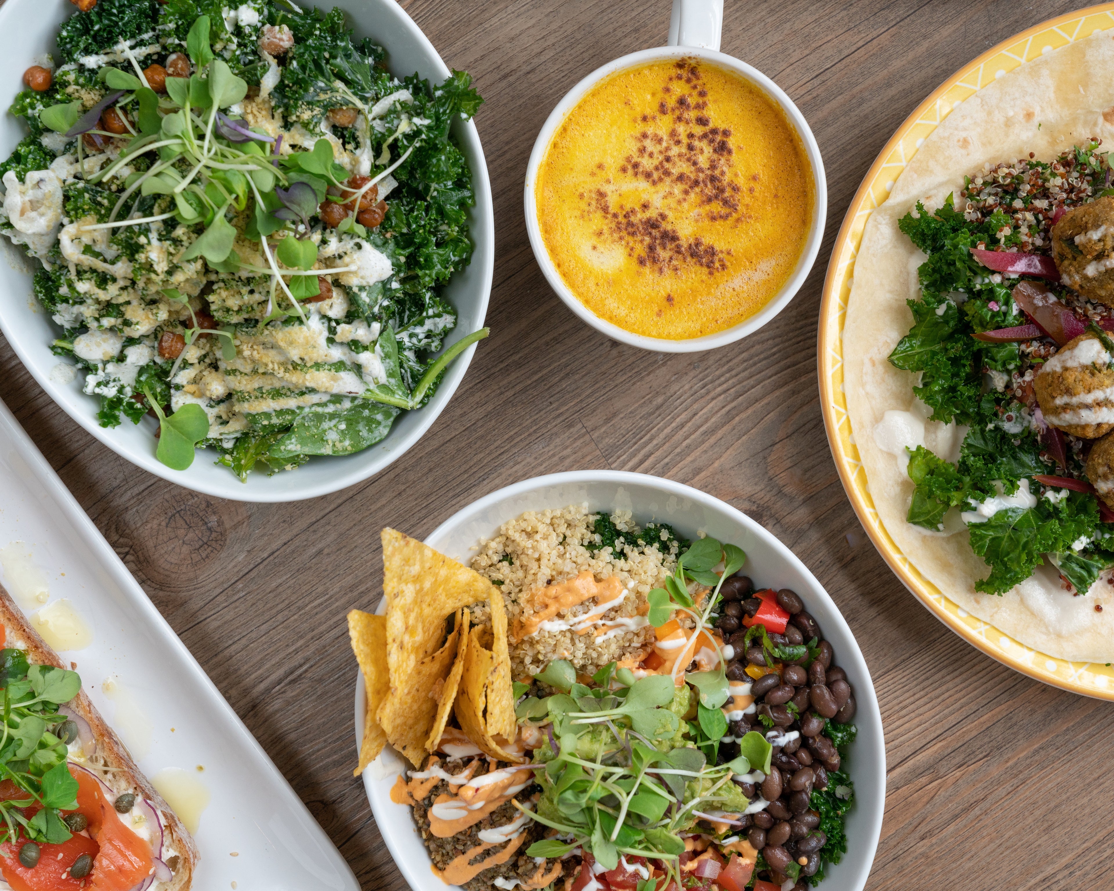 A variety of fresh salads, wraps, and bowls made with vibrant hydroponic plants, arranged on a dining table.
